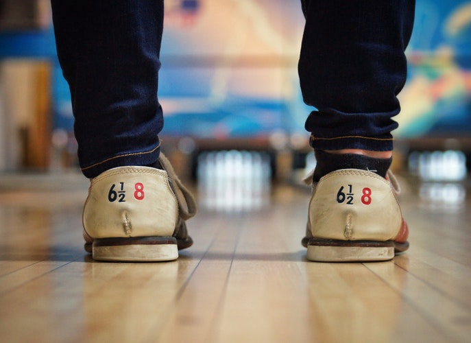 Closeup of bowling shoes being worn in front of a bowling lane
