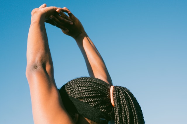 Cropped photo of woman stretching arms against sky
